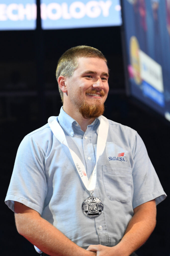 Benjamin Strupp on stage with a medal around his neck